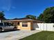 A yellow single-story home with a well-manicured lawn and privacy fence is shown on a sunny day at 8210 Marigold Ave, Tampa, FL 33614