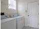 Functional laundry area with side-by-side washer and dryer units and storage shelving at 12720 Whitney Meadow Way, Riverview, FL 33578
