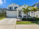 Charming two-story home featuring a well-manicured lawn, two-car garage, and inviting front porch with palm trees at 1439 Gopher Loop, Tarpon Springs, FL 34689