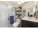 Bright bathroom featuring a glass-enclosed shower, black vanity, and decorative shelves with plants at 17503 Edinburgh Dr, Tampa, FL 33647