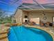 Spacious screened-in pool area with a hot tub, outdoor seating, and a ceiling fan for added comfort at 17503 Edinburgh Dr, Tampa, FL 33647