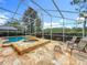 Enclosed pool area featuring an in-ground pool, hot tub, stone tile patio, and a seating area for outdoor relaxation at 17503 Edinburgh Dr, Tampa, FL 33647