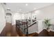 Open hallway with dark wood floors, staircase with wrought iron railing, and arched doorways at 17909 Howsmoor Pl, Lutz, FL 33559