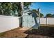 A quaint light-blue backyard shed, complemented by a birdhouse and white vinyl fence, amidst lush greenery at 2736 45Th N Way, St Petersburg, FL 33713