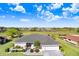 An aerial view of a well-maintained home with a lush green lawn, scenic surroundings, and a nearby pond at 303 Cranston Pl, Sun City Center, FL 33573