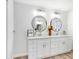 All-white bathroom with double vanity, granite counters and round mirrors at 303 Cranston Pl, Sun City Center, FL 33573