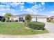 Charming home with lush green lawn, complemented by manicured landscaping, and a freshly paved driveway at 303 Cranston Pl, Sun City Center, FL 33573