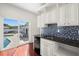 This wet bar includes white cabinetry, dark countertops, a tile backsplash, and sliding doors to the pool area at 4837 W Bay Court Ave, Tampa, FL 33611