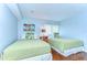 Twin bedroom with light green quilted bedspreads, palm tree pillows, and hard wood floors at 5019 Mill Pond Rd # 3128, Wesley Chapel, FL 33543