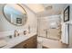 Bathroom with wood vanity, round mirror, and tub-shower with glass doors at 575 Hickorynut Ave, Oldsmar, FL 34677