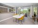 Bright dining area featuring a modern white table with yellow chairs and natural light from the sliding door at 575 Hickorynut Ave, Oldsmar, FL 34677