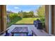 A covered patio with a grill, table and chairs overlooks a lush backyard with mature landscaping and a black metal fence at 6338 Springline Pl, Apollo Beach, FL 33572