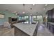 Open-concept kitchen and living room featuring a large granite island, tile flooring, and stainless steel appliances at 6338 Springline Pl, Apollo Beach, FL 33572