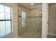 Shower with tiled walls and frameless glass door, complemented by a window for natural lighting at 6527 Grapewood Rd, Spring Hill, FL 34609