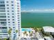 Stunning view of condo building and waterfront, featuring community pool and tropical landscaping at 7200 Sunshine Skyway S Ln # 16G, St Petersburg, FL 33711