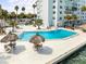 Outdoor pool area surrounded by lounge chairs and lush palm trees overlooking the ocean at 7200 Sunshine Skyway S Ln # 16G, St Petersburg, FL 33711
