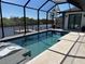 Screened in pool with poolside lounge chairs, river view, and travertine patio at 9514 Snapper Cir, Port Charlotte, FL 33981