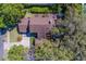 A high aerial image that showcases the home's brown roof and lush, tropical, backyard oasis with great patio space at 1439 Wetherington Way, Palm Harbor, FL 34683