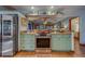 Bright kitchen featuring sage-colored cabinets, granite counters, stainless appliances, and an open layout with wood-look tile floors at 1439 Wetherington Way, Palm Harbor, FL 34683