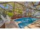 Sparkling pool enclosed by a screen cage, framed by brick pavers and lush landscaping at 1439 Wetherington Way, Palm Harbor, FL 34683