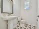 Bathroom featuring patterned tile floor, pedestal sink, toilet and a modern mirror and fixtures at 1558 Merrythought Ln, Sarasota, FL 34240