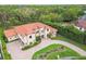 Aerial view of a Mediterranean-style home with a red tile roof, lush landscaping, and a brick driveway at 17005 Madres De Avila, Tampa, FL 33613