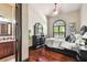 Cozy bedroom with dark wood floors, an arched window, and a view into the bathroom at 17005 Madres De Avila, Tampa, FL 33613