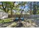Fenced backyard with mature trees and outdoor seating, offering a private and serene outdoor space at 1887 Oak Forest E Dr, Clearwater, FL 33759