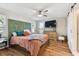Charming bedroom with colorful headboard, hardwood floors, and rustic storage unit with flat screen television at 1887 Oak Forest E Dr, Clearwater, FL 33759