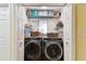 Functional laundry room with modern washer and dryer, shelving, and organized storage at 1887 Oak Forest E Dr, Clearwater, FL 33759