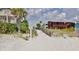 Sandy beach path with wooden railing leading to the beach with homes nearby at 19829 Gulf Blvd # 601, Indian Shores, FL 33785