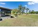 Backyard view with a well-maintained lawn, mature trees, decorative shrubbery, and a screened-in lanai at 2007 E View Dr, Sun City Center, FL 33573
