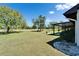 Backyard showcasing the well-maintained lawn, mature trees, and a screened-in lanai at 2007 E View Dr, Sun City Center, FL 33573