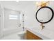 Beautiful bathroom featuring modern fixtures, a bathtub with shower and round decorative mirror at 2650 E Vina Del Mar Blvd, St Pete Beach, FL 33706