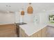 Spacious kitchen island features a flat cooktop, white countertops, modern wicker light fixtures, and wooden cabinets at 2650 E Vina Del Mar Blvd, St Pete Beach, FL 33706