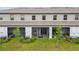 Backyard view of townhomes with covered patios, green grass and young trees at 3629 Bellmeade Ct, Wesley Chapel, FL 33543