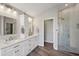 Bright bathroom featuring dual sinks, a shower with glass door, and wood-look floors at 3994 Belmoor Dr, Palm Harbor, FL 34685
