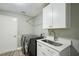 Well-equipped laundry room with modern washer and dryer, utility sink, and storage cabinets at 3994 Belmoor Dr, Palm Harbor, FL 34685