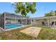 A backyard showcasing a screened-in pool, patio, and outdoor seating area at 5103 Town N Country Blvd, Tampa, FL 33615