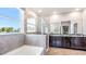 Spacious bathroom with gray tiles, a soaking tub, separate shower, double granite vanity and large windows at 5309 Oxford Gray Rd, Wesley Chapel, FL 33545