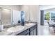 Bathroom with double granite top vanity and modern fixtures, offering a view of the home office and exterior at 5309 Oxford Gray Rd, Wesley Chapel, FL 33545