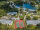 Aerial view of a community with tennis courts, a lake, pool, and lush greenery at 1333 Shady Pine Way # F, Tarpon Springs, FL 34688