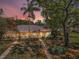 A single-story home featuring a fenced yard and mature trees, all bathed in the soft glow of a colorful sunset sky at 1333 Shady Pine Way # F, Tarpon Springs, FL 34688