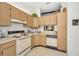 Functional kitchen featuring light wood cabinets, white appliances, and a view to another room at 1333 Shady Pine Way # F, Tarpon Springs, FL 34688