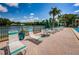 Scenic pool deck with lounge chairs, tables, umbrellas, and a tranquil lakeside view at 1333 Shady Pine Way # F, Tarpon Springs, FL 34688