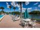 Relaxing pool deck with lounge chairs, tables, umbrellas, and a tranquil lakeside view at 1333 Shady Pine Way # F, Tarpon Springs, FL 34688
