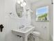 A white bathroom featuring a pedestal sink, oval mirror, and tiled walls at 1401 E North St, Tampa, FL 33604