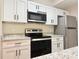 Modern kitchen with white cabinets, granite countertops, stainless steel appliances including a range and refrigerator at 17114 Carrington Park Dr # 207, Tampa, FL 33647