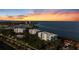 Stunning aerial view of waterfront condos with lush landscaping, marina, and vibrant sunset skies at 2410 Harbourside Dr # 142, Longboat Key, FL 34228