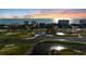 Scenic aerial of golf course with ponds, lush fairways, and surrounding coastal community under a vibrant sunset sky at 2410 Harbourside Dr # 142, Longboat Key, FL 34228